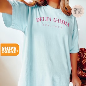 May include: A light blue t-shirt with the text "DELTA GAMMA EST. 1873" in pink lettering.