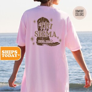 a woman standing on a beach wearing a pink shirt