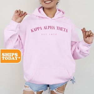 May include: Pink hooded sweatshirt with the text "Kappa Alpha Theta Est. 1870" in pink.