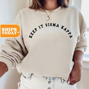 May include: A beige sweatshirt with the text "Keep It Sigma Kappa" printed in black.