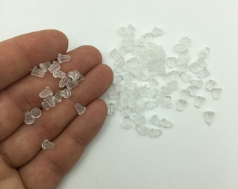 May include: A large quantity of clear plastic earring backs. The backs are small and have a rounded shape.