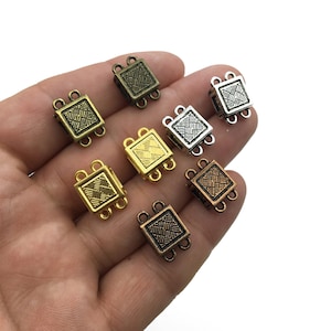 Op de afbeelding: Assortiment van acht vierkante magnetische sluitingen voor het maken van sieraden. De sluitingen zijn verkrijgbaar in verschillende metallic afwerkingen, waaronder goud, zilver, brons en koper.