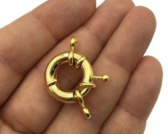 Könnte beinhalten: Goldfarbener Metallverschluss mit einem runden Ring und einem Hakenverschluss. Der Verschluss ist für Halsketten, Armbänder oder anderen Schmuck gedacht.
