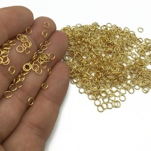 May include: A large pile of gold jump rings. The rings are small and round, and they are ideal for jewellery making.