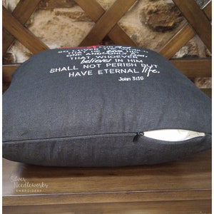 May include: Black throw pillow with white embroidered text that reads "For God so loved the world that He gave His one and only Son, that whoever believes in Him shall not perish but have eternal life. John 3:16".