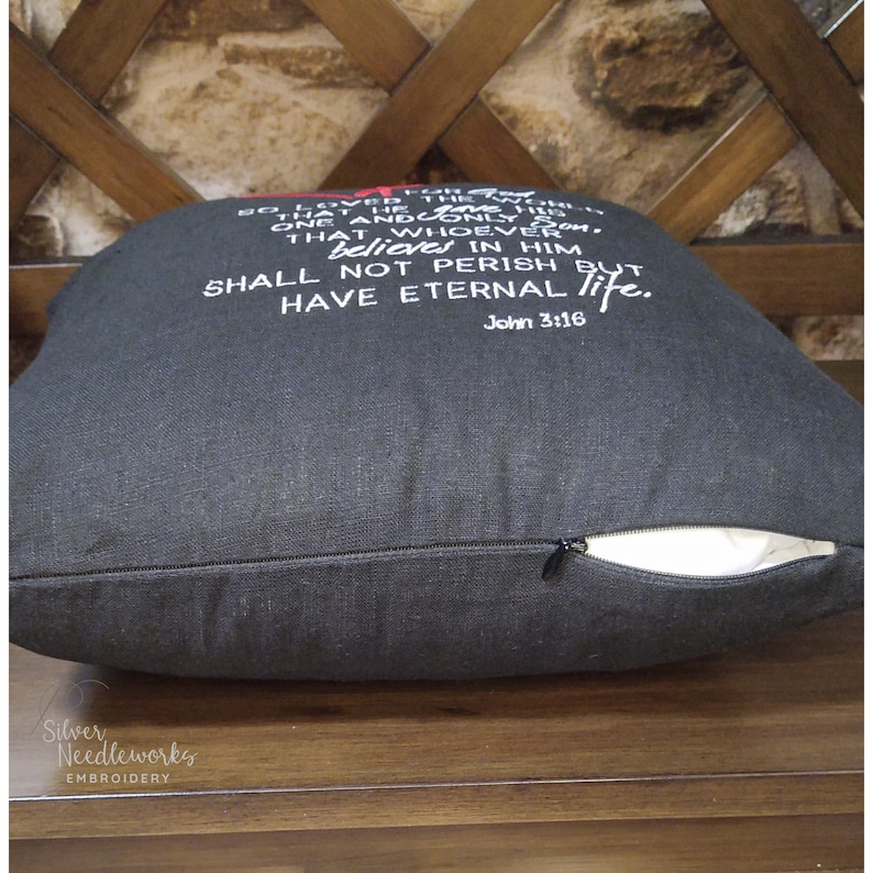 May include: Black throw pillow with white embroidered text that reads "For God so loved the world that He gave His one and only Son, that whoever believes in Him shall not perish but have eternal life. John 3:16".