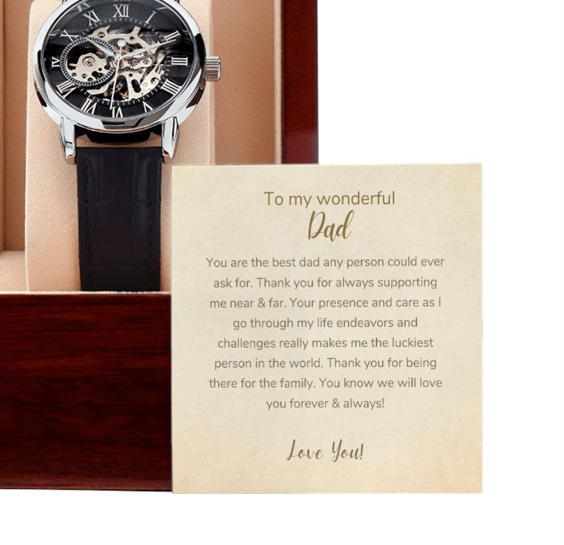 May include: A wooden box with a silver watch and a card inside. The card has a message that reads "To my wonderful Dad. You are the best dad any person could ever ask for. Thank you for always supporting me near & far. Your presence and care as I go through my life endeavors and challenges really makes me the luckiest person in the world. Thank you for being there for the family. You know we will love you forever & always! Love You!"
