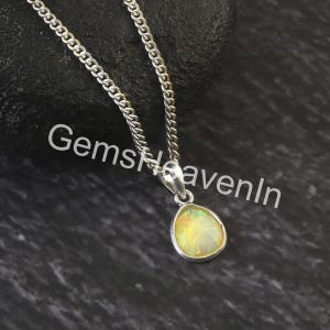 May include: A silver necklace with a pendant featuring a pear-shaped, iridescent gemstone. The pendant is set in a silver bezel and hangs from a silver chain. The text "GemsHeavenIn" is visible in the image.