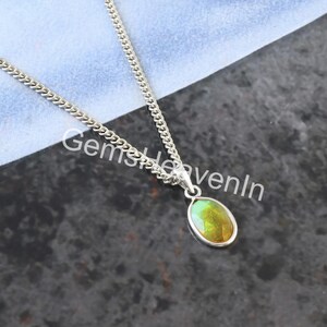 May include: A silver chain necklace with an oval pendant. The pendant features a gemstone with green and yellow hues, set in a silver bezel. The text "GemsHeavenIn" is visible on the image.