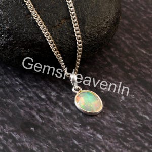 May include: A silver necklace with an oval pendant. The pendant has a colourful opal stone set in a silver bezel. The chain is a classic curb link style. The text "GemsHeavenIn" is visible in the image.