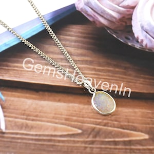 May include: A silver necklace featuring a pear-shaped pendant with an iridescent stone. The chain is a curb style. The text "GemsHeavenIn" is visible in the image.