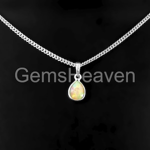 May include: A silver necklace with a pear-shaped opal pendant. The opal has a mix of yellow, white, and orange hues. The chain is a curb style, and the pendant is set in a silver bezel. The text "GemsHeaven" is visible.