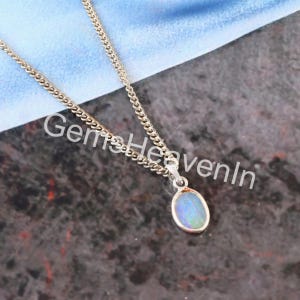 May include: Silver necklace featuring an oval opal pendant. The opal has blue, green, and white hues. The chain is a fine curb link design. The image includes the text "Gems HeavenIn".