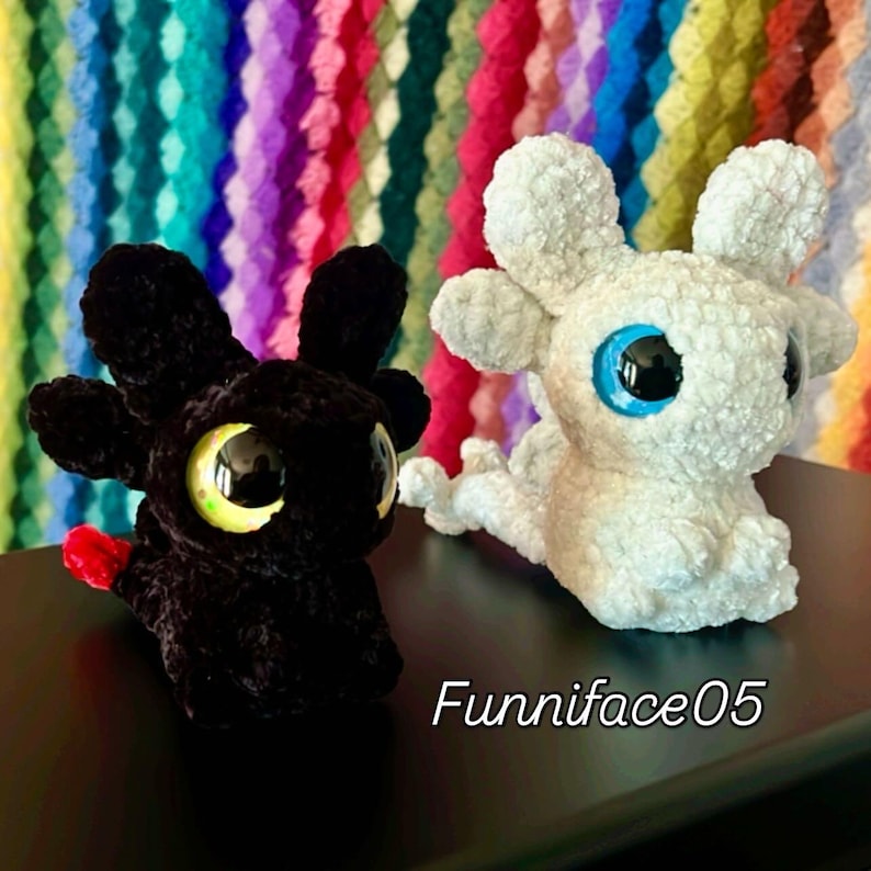 K&ouml;nnte beinhalten: Zwei geh&auml;kelte Drachen-Pl&uuml;schtiere. Einer ist schwarz mit gelben und schwarzen Augen und einer roten Flosse. Der andere ist wei&szlig; mit blauen Augen. Der Text "Funniface05" ist unten rechts in Wei&szlig; geschrieben.