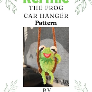 May include: A crochet pattern for a Kermit the Frog car hanger. The pattern is low-sew and includes instructions for making a green frog with a red mouth and white eyes, hanging from a brown rope.