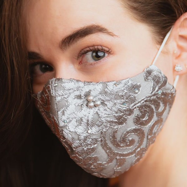 Graceful, silvery grey, three layered, reusable lace face mask with faux diamanté’s and grey pearls scattered randomly. Cosy cotton lining.