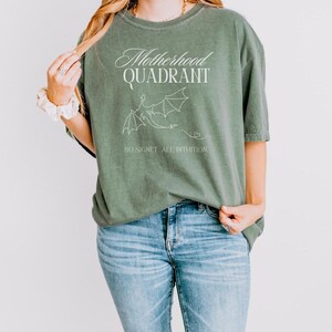 A model wears a comfort colors shirt in moss green. It is inspired by Fourth Wing merch