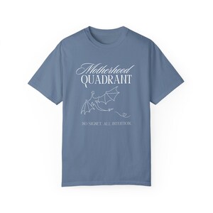 A flat lay shirt in denim blue. It says Motherhood Quadrant and is inspired by the Fourth Wing Series