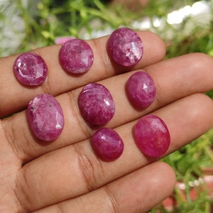 Pu&ograve; includere: Una collezione di otto pietre preziose rosa sfaccettate di forma ovale. Le pietre preziose sono esposte su una mano.