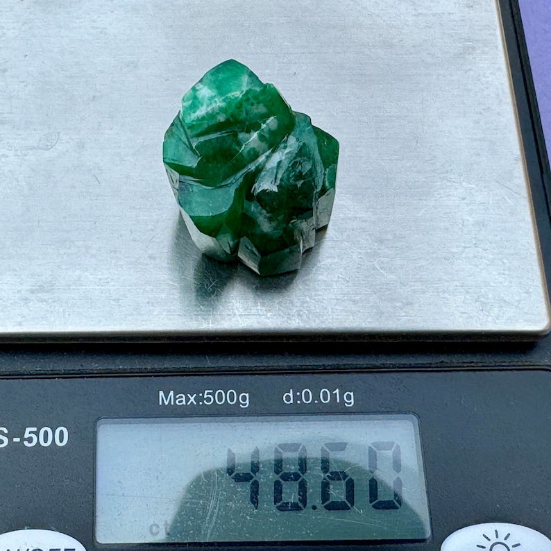 May include: A green jade stone weighing 48.60 grams on a digital scale. The scale reads "Max:500g d:0.01g".