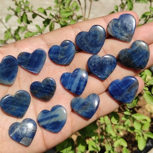 Könnte beinhalten: Eine Sammlung von 14 polierten, herzförmigen Steinen in Blau. Die Steine haben eine hellblaue Farbe mit dunkleren blauen Streifen und Adern.