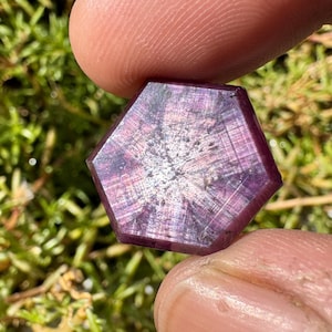 May include: A faceted, hexagonal, purple gemstone with a star-like pattern in the centre.