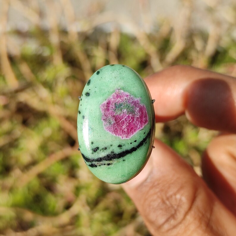 Peut inclure: Pierre pr&eacute;cieuse verte de forme ovale avec des veines noires et un centre rose et vert.