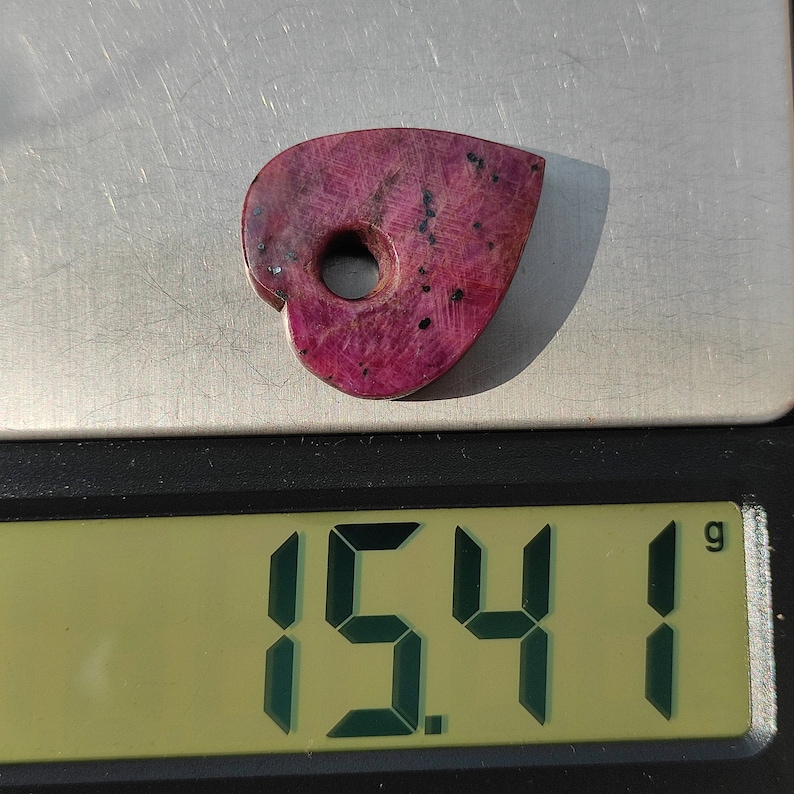 May include: A pink heart-shaped stone with a hole in the center, weighing 15.41 grams.