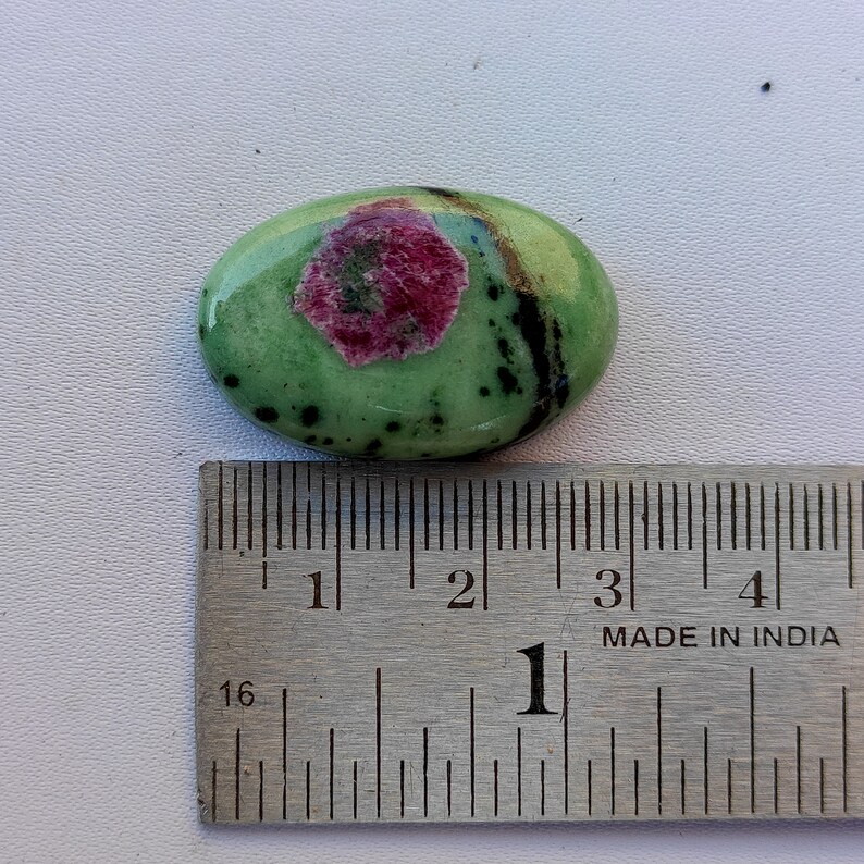 Peut inclure: Pierre pr&eacute;cieuse ovale verte avec un centre rose et noir, mesurant environ 2,5 cm de long, &agrave; c&ocirc;t&eacute; d'une r&egrave;gle.