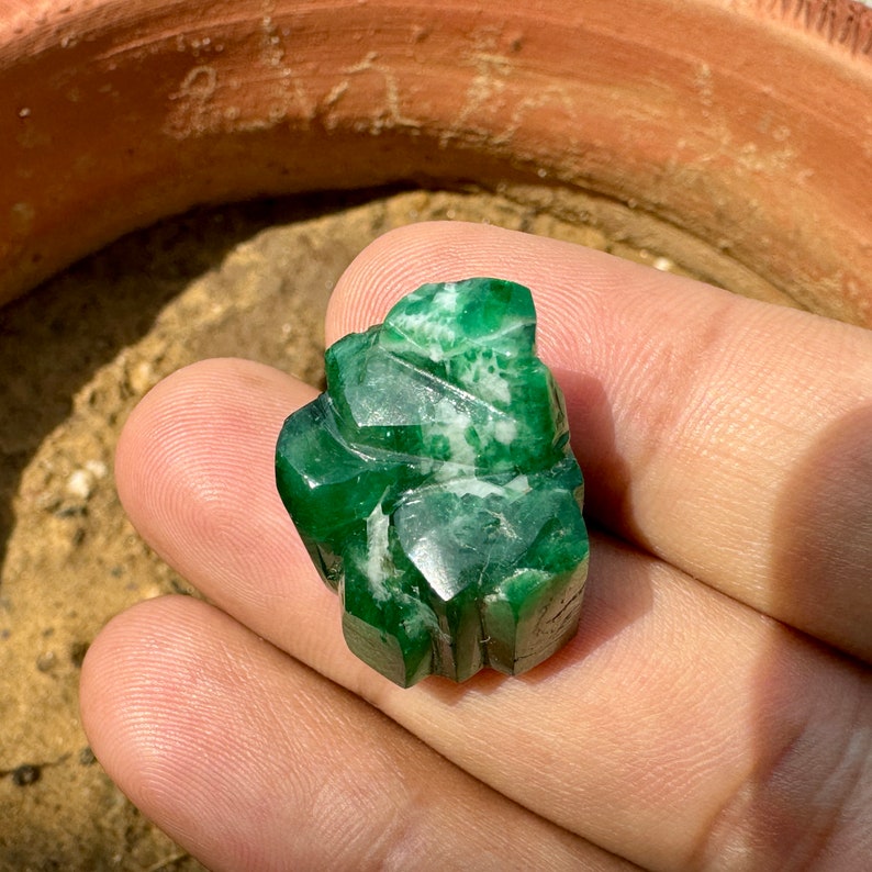 May include: A carved green gemstone with white veins, resembling a stylized leaf or flower.