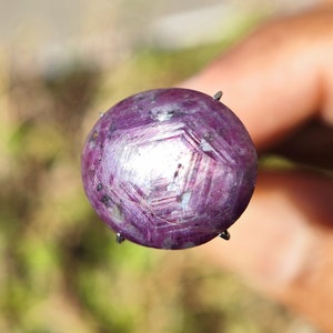 Peut inclure: Une pierre précieuse ronde de couleur violette avec un motif en forme d'étoile sur la surface. La pierre précieuse est sertie dans une monture à griffes en argent.
