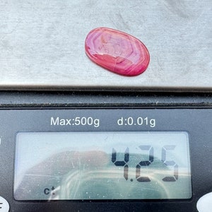 May include: A pink and white agate cabochon gemstone weighing 4.25 grams on a digital scale. The scale reads "Max:500g d:0.01g".
