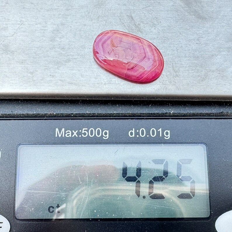 May include: A pink and white agate cabochon gemstone weighing 4.25 grams on a digital scale. The scale reads "Max:500g d:0.01g".