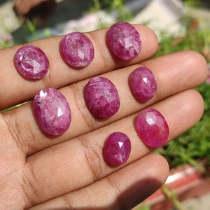 Pu&ograve; includere: Una collezione di otto pietre preziose di rubino rosa di forma ovale e sfaccettate. Le pietre preziose sono di varie dimensioni e sono esposte su una mano.
