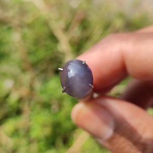 May include: A gray oval-shaped gemstone with a metallic sheen, set in a silver prong setting.