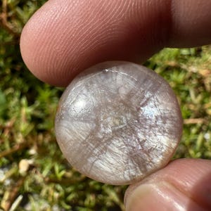 以下が含まれることがあります： 丸い白と灰色の宝石で、キラキラと虹色に輝く仕上げになっています。石には、独特で自然なラインと渦巻き模様があります。