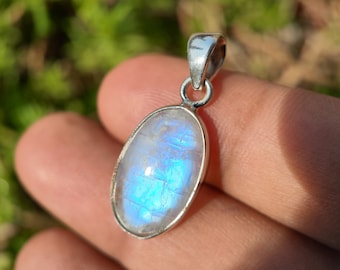 May include: A silver pendant with a large oval moonstone. The moonstone is iridescent with a blue and white sheen.