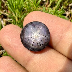 Puede incluir: Un cabujón de zafiro estrellado de color púrpura oscuro con una estrella de seis puntas.