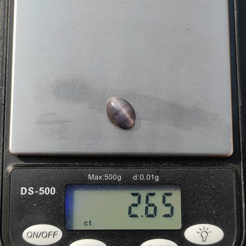K&ouml;nnte beinhalten: Nahaufnahme eines grauen Edelsteins auf einer digitalen Waage. Die Waage zeigt 2,65 ct an.
