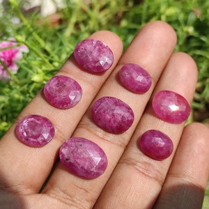 Pu&ograve; includere: Otto pietre preziose rosa di forma ovale con bordi sfaccettati. Le pietre preziose sono esposte su una mano.