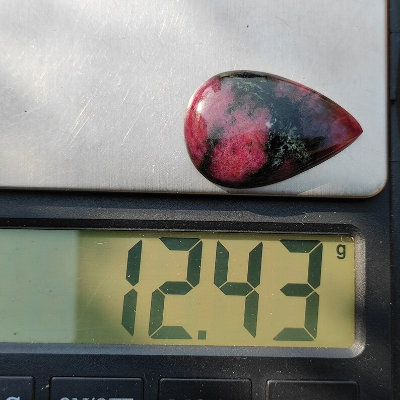 Puede incluir: Una piedra preciosa rosa y verde que pesa 12,43 gramos en una b&aacute;scula digital.