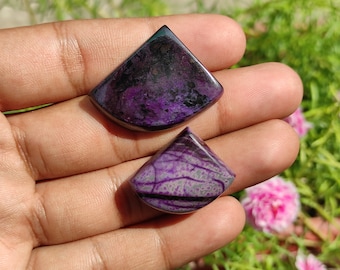 Op de afbeelding: Twee paarse en zwarte cabochons in een traanvorm. De stenen hebben een marmerpatroon en zijn gezet in een zilverkleurige zetting.