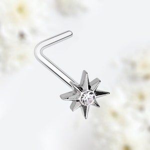 May include: Silver nose ring with a star-shaped charm and a clear crystal in the center.