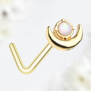 May include: Gold nose ring with a crescent moon design and a white opal gemstone.