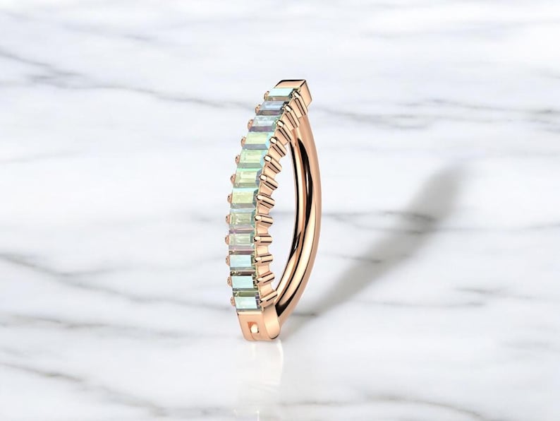 Op de afbeelding: Gebogen halter uit ros&eacute;goud met een rij rechthoekige, iriserende edelstenen. Dit sieraad voor body piercing heeft een gebogen vorm en een gepolijste afwerking. De edelstenen vertonen een subtiele, veelkleurige glans.