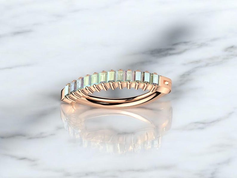 Op de afbeelding: Ros&eacute;gouden ring met een rij rechthoekige, iriserende edelstenen. De edelstenen zijn dicht op elkaar geplaatst, waardoor een doorlopende band van kleur ontstaat. De ringband heeft een gladde, gepolijste afwerking.