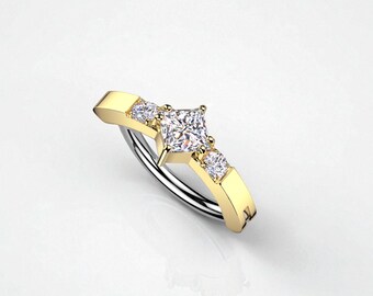 May include: A gold and silver ring with a square-cut center stone and two smaller stones on either side. The ring has a gold band and a silver inner band, creating a two-tone effect. The ring is set against a white background.