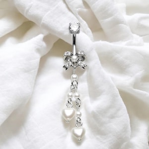 May include: A silver belly button ring with a crystal bow and a dangling chain of pearls and heart-shaped charms.