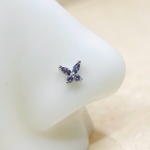 May include: A silver nose ring with a small butterfly design featuring purple gemstones.