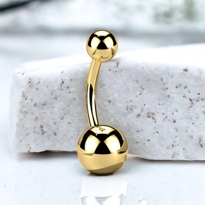 Puede incluir: Anillo de ombligo dorado con dos bolas redondas.